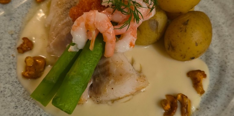 Torsk med krämig vitvinssås, räkor, rom, sparris, småpotatis och smörstekta kantareller.
