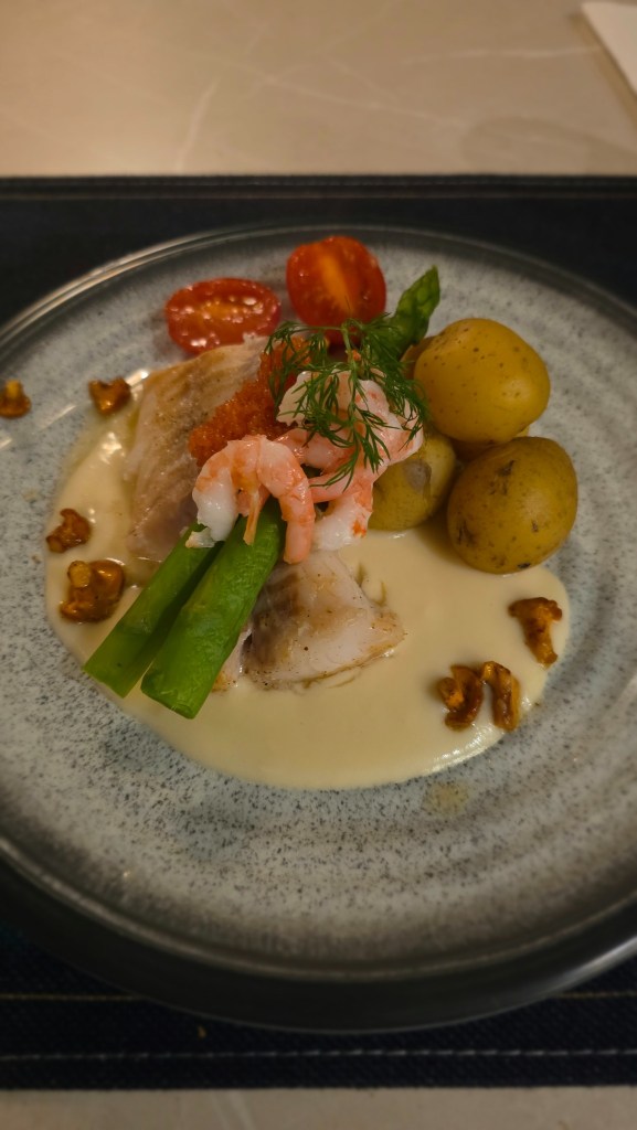 Torsk med krämig vitvinssås, räkor, rom, sparris, småpotatis och smörstekta kantareller.